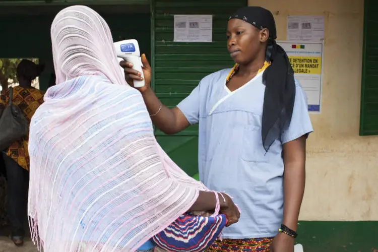 
	Mulher mede a temperatura de outra por suspeita de ebola na fronteira entre a Guin&eacute; e o Mali: foram ao todo seis casos fatais
 (Joe Penney/Reuters)