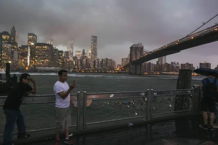 
	Turistas na Brooklyn Bridge para fotografar a chegada da tempestade tropical Arthur
 (Lucas Jackson/Reuters)