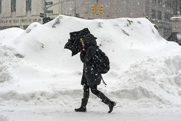 Mulher usa um guarda-chuva para se proteger da neve enquanto caminha nas ruas de Manhattan, em Nova York (Zoran Milich/Reuters)