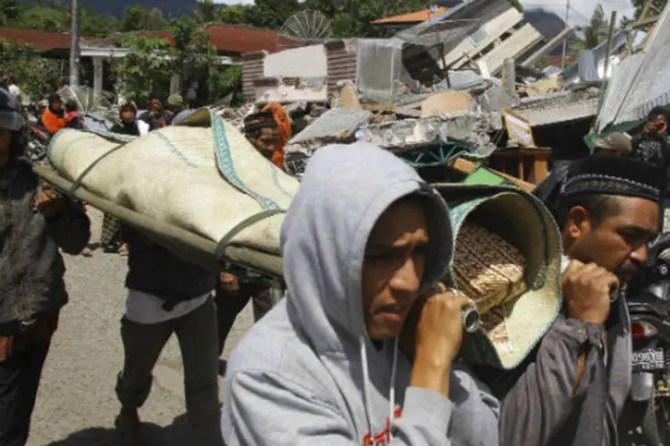 Parentes carregam corpo de vítima encontrado em escombros após terremoto que atingiu a Indonésia ( REUTERS/Roni Bintang)