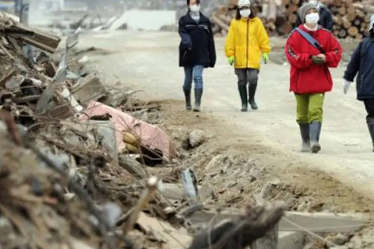 Japoneses caminham por uma rua, em um cenário de destruição causado pelo terremoto de março no país (Toshifumi Kitamura/AFP)