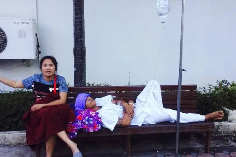 Mulher acena ao lado de um paciente após evacuar um hospital durante um terremoto em Chiang Rain, no norte da Tailândia (Reuters)