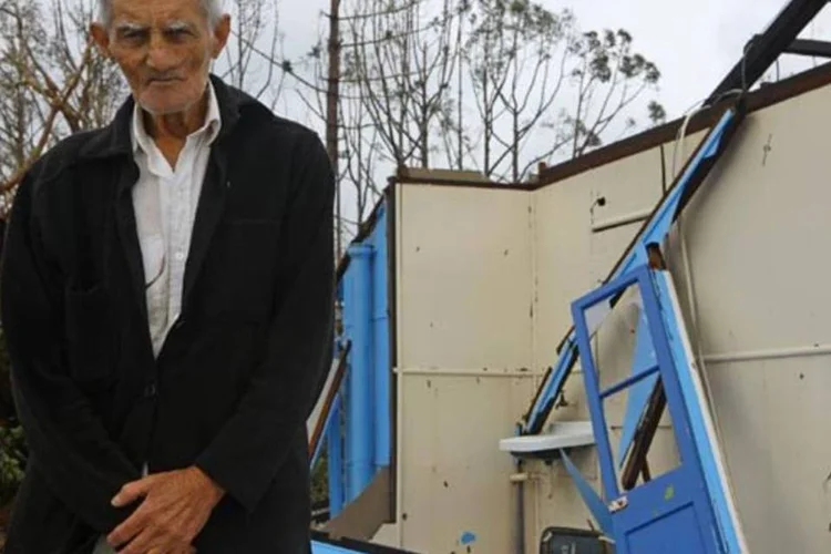 Theo, morador de Cardwell, na Austrália, ao lado de sua casa, destruída pelo ciclone Yasi (Jonathan Wood/Getty Images)