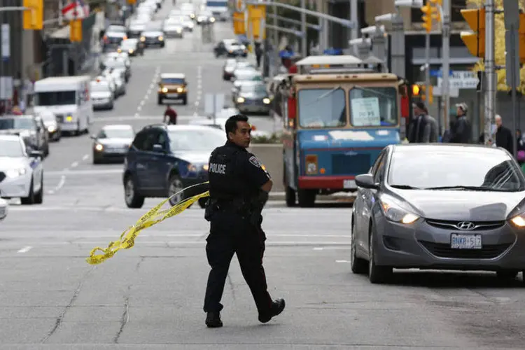 
	Policial cerca rua ap&oacute;s tiroteio: demora para conseguir passaporte estava ligada &agrave; ficha criminal de Bibeau
 (Blair Gable/Reuters)