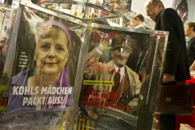 
	Capas da &quot;Titanic&quot; com Angela Merkel e Adolf Hitler s&atilde;o exibidas durante a Feira do Livro: a revista manifestou o seu apoio &agrave; revista sat&iacute;rica francesa Charlie Hebdo, que publicou caricaturas de Maom&eacute;
 (John Macdougall/AFP)