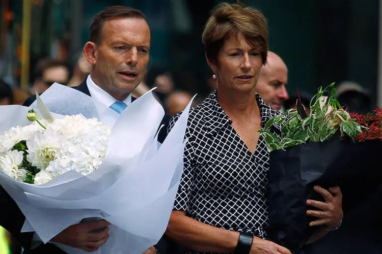 O premiê australiano Tony Abbott  e sua mulher Margie levam flores em homenagem às vítimas do sequestro em Sydney (REUTERS/David Gray)