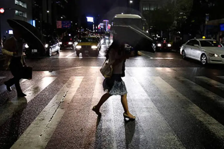 Pessoas atravessam uma rua em Tóquio segurando guardas-chuva após chegada da tempestade tropical Neoguri (REUTERS/Yuya Shino)