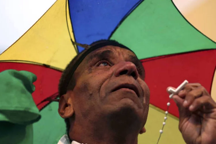 Homem segura terço, enquanto torce para o Brasil (Stefano Rellandini / Reuters)
