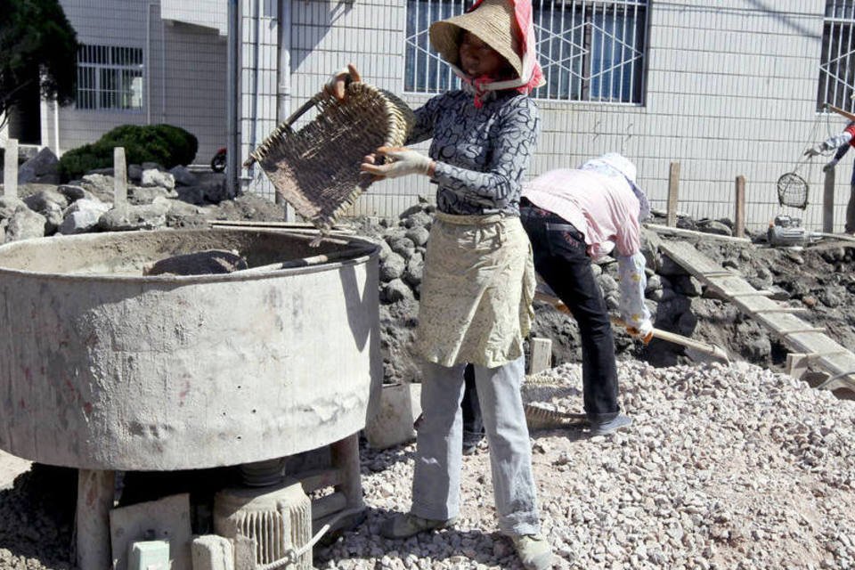 Trabalhadora mistura cimento em planta de construção em Dali, na China (Doug Kanter/Bloomberg)