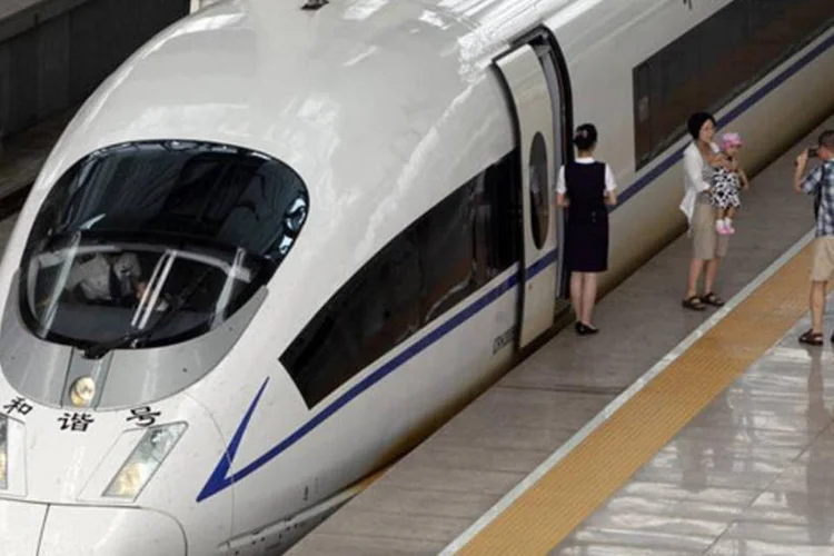 Passageira tira foto em frente a um trem bala estacionado na estação sul de Pequim, na China (Jason Lee/Reuters)