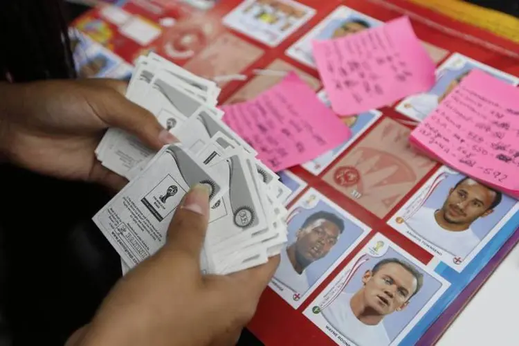 Mulher procura novas figurinhas do álbum da Copa do Mundo de 2014, em um cento de trocas de uma rua de Lima, no Peru (Mariana Bazo/Reuters)