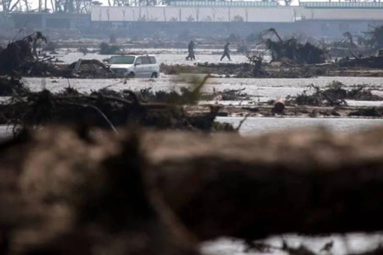 Oficiais da defesa-civil caminham em área devastada avaliando as perdas após o terremoto e o tsunami (Getty Images)