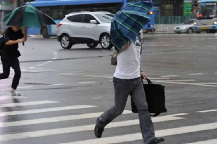Sul-coreanos tentam se proteger da chuva durante a ventania, em Seul (Kim Jae-Hwan/AFP)