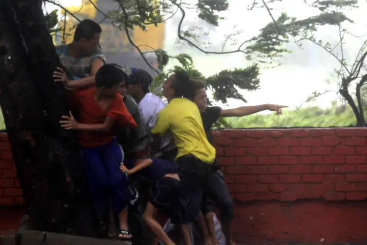 
	Em Manila, Filipinas, pessoas se protegem em uma &aacute;rvore dos ventos provocados pelo tuf&atilde;o Rammasun
 (REUTERS/Romeo Ranoco)