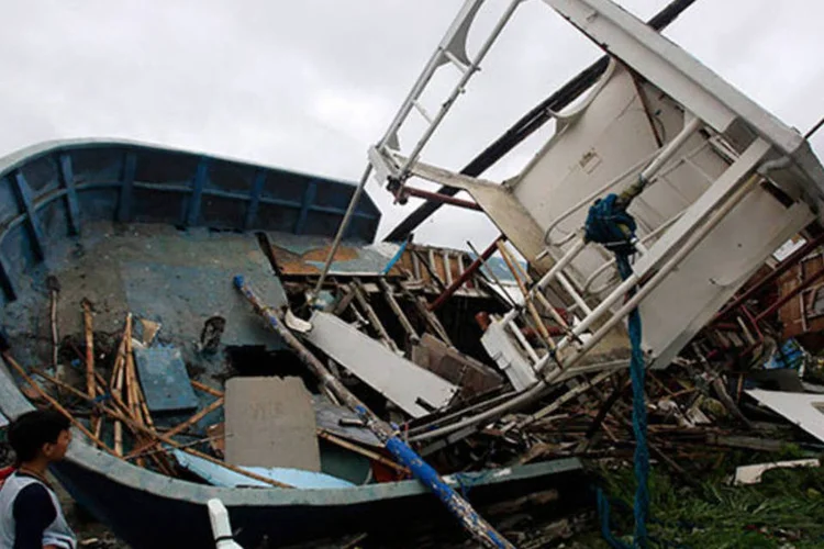 Crianças olham para barco destruído pelos fortes ventos trazidos pelo Tufão Rammasun às Filipinas (REUTERS/Romeo Ranoco)