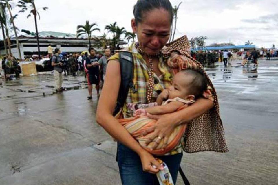 Mulher com um bebê no colo chora em meio a devastação de uma área atingida por Haiyan (Getty Images)