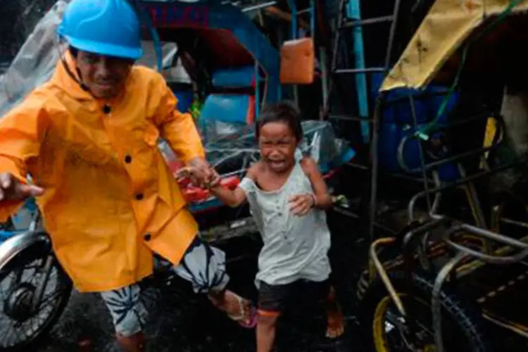 Funcionário municipal retira uma criança de casa, em Manila, por causa do tufão
 (Ted Aljibe/AFP)