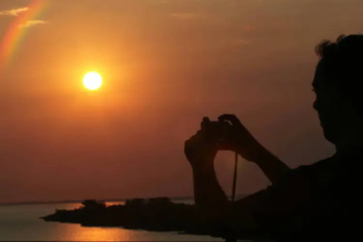 Turista tira foto de pôr-do-sol em rio do Uruguai (Diego Giudice/Bloomberg News)