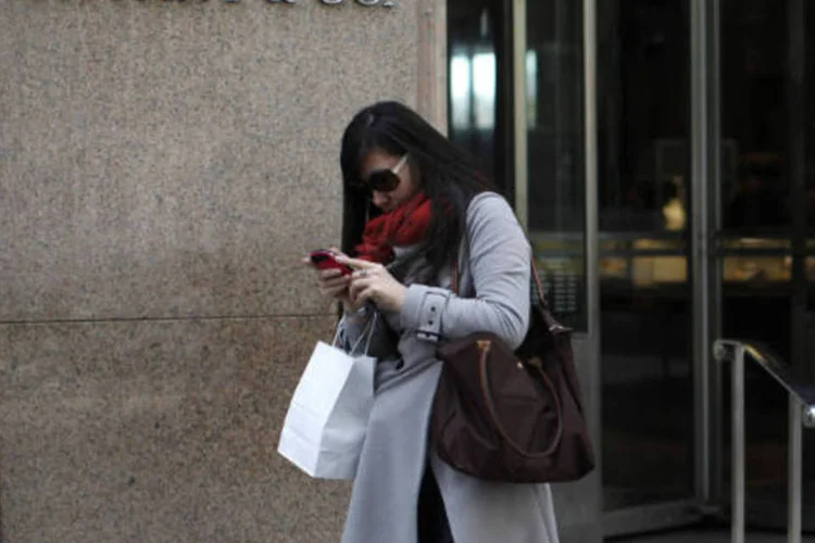 Chineses: Turista checa seu smartphone depois de comprar na luxuosa joalheria Tifany & Co, em Nova York. Chineses gastaram 41 % a mais em viagens ao exterior em 2012 do que no ano anterior, superando os cerca de US$ 84 bilhões gastos por alemães e norte-americanos. (REUTERS/Mike Segar)