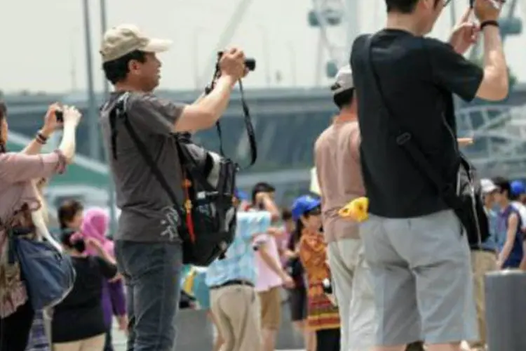 Turistas no parque Merlion, em Singapura: "de uma maneira geral, a indústria do turismo cresce mais rápido que o PIB", afirma especialista (Roslan Rahman/AFP)