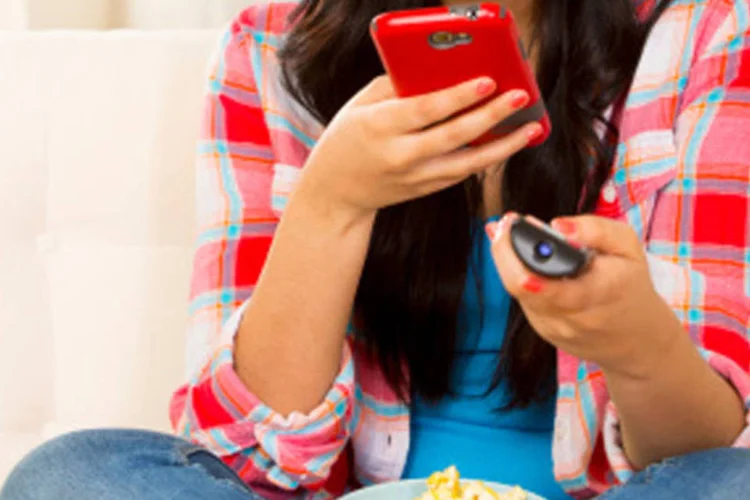 Pessoa usa controle remoto e celular ao mesmo tempo (Getty Images/Getty Images)