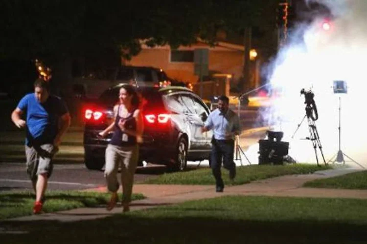 Equipe de TV se proteger de gás lançado pela polícia em Ferguson, Missouri (Scott Olson/AFP)