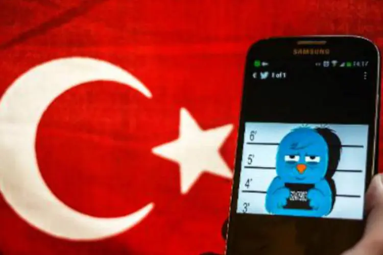 Montagem com imagem do Twitter em smartphone com bandeira da Turquia ao fundo: decisão referente ao YouTube foi comunicada aos servidores de internet (Ozan Kose/AFP)