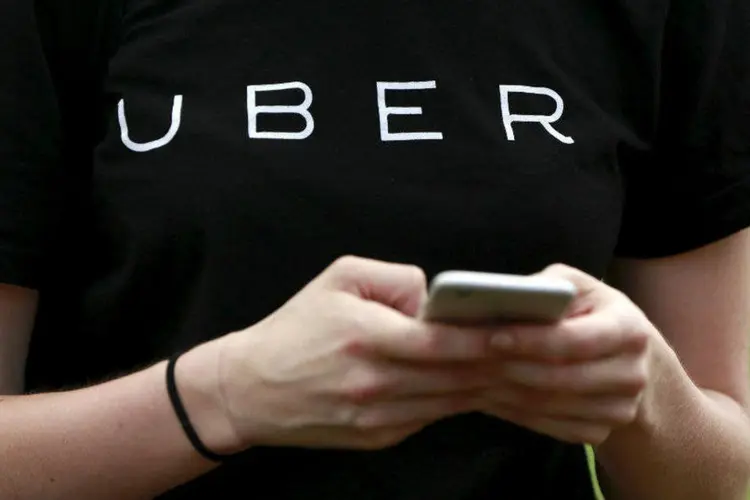 
	Pessoa com camiseta do Uber usa celular: a empresa de transporte solicitado est&aacute; lan&ccedil;ando um novo recurso, chamado Trip Experiences
 (Shannon Stapleton/Reuters)