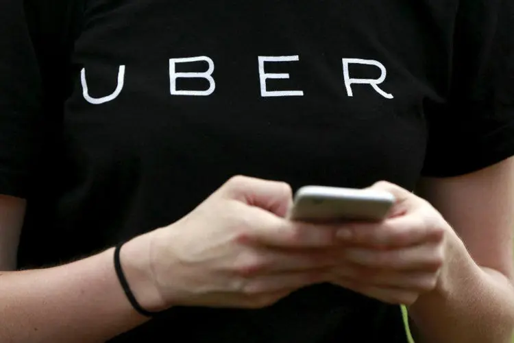 
	Pessoa com camiseta do Uber usa celular: o Uber revelou que 50 mil nomes e n&uacute;meros de licen&ccedil;a de seus motoristas foram acessados indevidamente
 (Shannon Stapleton/Reuters)