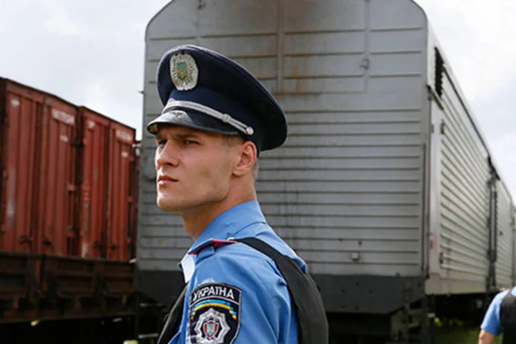 Policiais observam a chegada do trem carregando os restos mortais das vítimas do voo MH17 da Malaysia Airlines  (REUTERS/Gleb Garanich)