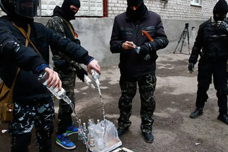 Homens mascarados esvaziam garrafas de vodka para usar como bombas em frente a posto policial em Slaviansk: a Rússia nega estar dando qualquer apoio aos militantes (Gleb Garanich/Reuters)
