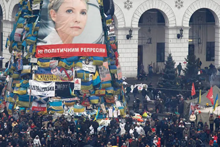 Manifestantes próximos a pôster com foto de Yulia Tymoshenko na Praça da Independência, em Kiev  (REUTERS/Vasily Fedosenko)