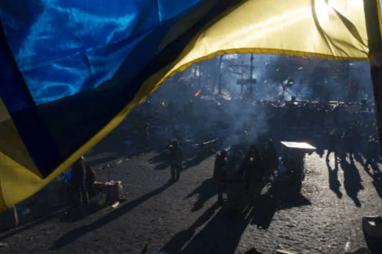 Bandeira da Ucrânia com barricadas de manifestantes ao fundo, em Kiev: mortes ocorreram nos protestos dos últimos dias (Thomas Peter/Reuters)