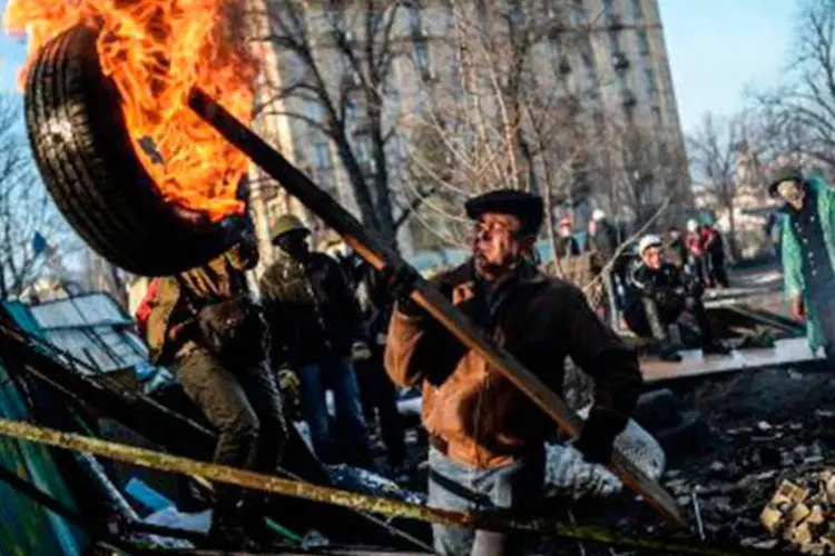 
	Um manifestante carrega uma bandeira em chamas durante protesto em Kiev, na Ucr&acirc;nia: o governo prop&otilde;e a realiza&ccedil;&atilde;o de uma grande confer&ecirc;ncia internacional de doadores&nbsp;
 (Bulent Kilic/AFP)