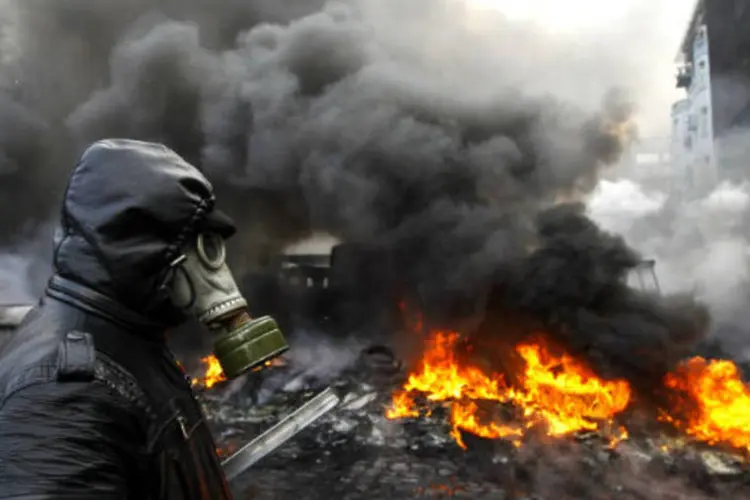 Em Kiev, na Ucrânia, um manifestante se protege usando uma máscara de gás durante um confronto com a polícia. Há meses cidadãos e policias entram em confronto na capital, depois do governo ucraniano desistir de negociar com a União Europeia. (23/1/2014)
 (REUTERS/Vasily Fedosenko)