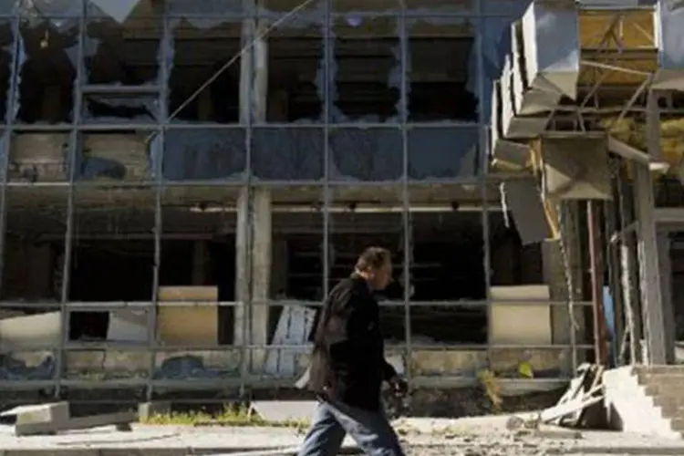 Ucraniano passa por prédio destruído em ataque recente no distrito de Kyivskyi, perto do aeroporto de Donetsk, em 7 de outubro
 (John MacDougall/AFP)