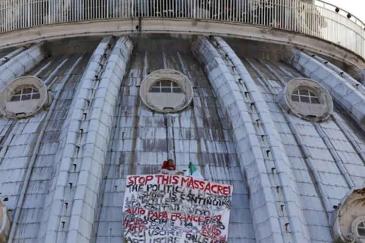 Homem escala cúpula da basílica de São Pedro, no Vaticano, para protestar contra crise: ele abriu um cartaz com frases sobre a crise econômica e contra o euro. (REUTERS/Alessandro Bianchi)