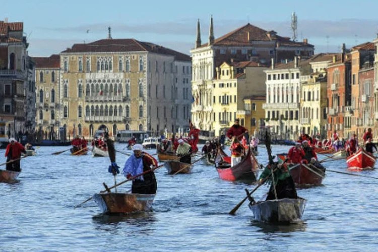 Mulheres em trajes tradicionais remam durante a tradicional corrida de Befana, nos canais de Veneza (Marco Secchi/Getty Images)