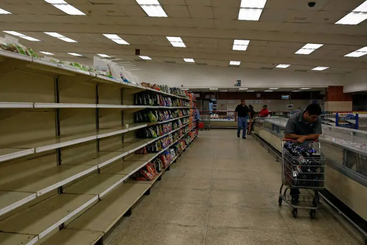 
	Pessoas compram comida em supermercado na Venezuela
 (Mariana Bazo / Reuters)