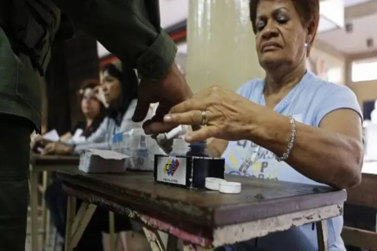 
	Mes&aacute;ria marca dedo de soldado com tinta durante elei&ccedil;&otilde;es na Venezuela: de acordo com os novos n&uacute;meros, Maduro obteve 7.559.349 votos (50,75%) e Capriles 7.296.876 (48,98%), uma diferen&ccedil;a de apenas 262.473.
 (Reuters)