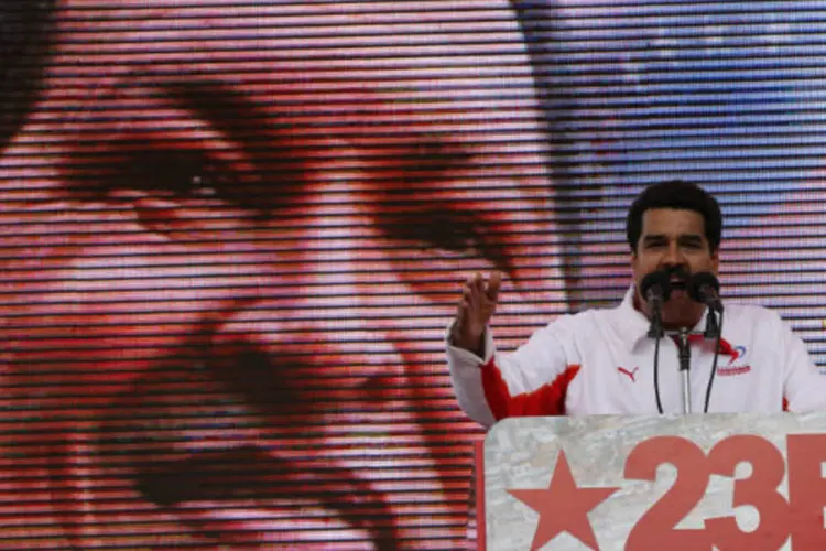 O vice-presidente da Venezuela, Nicolás Maduro, discursa para milhares de pessoas em Caracas com imagem de Hugo Chávez ao fundo (REUTERS/Jorge Silva)