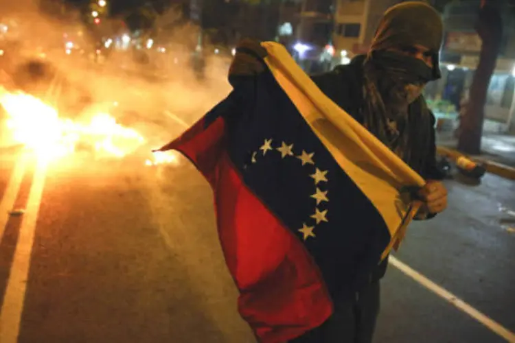 
	Manifestante corre com bandeira da Venezuela durante protesto em Caracas
 (REUTERS/Carlos Garcia Rawlins)