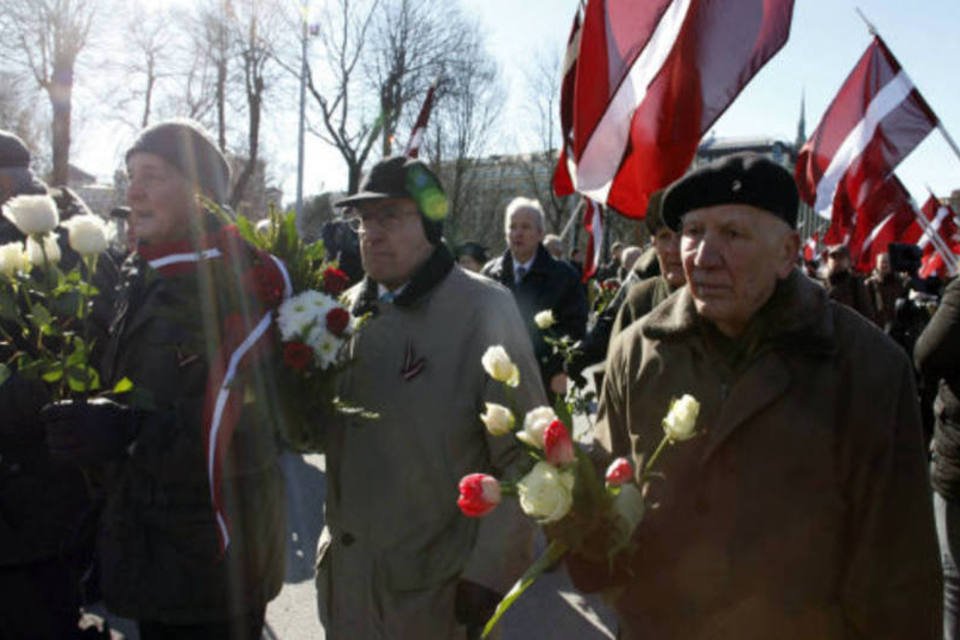 Homens carregam flores durante desfile anual para comemorar a unidade da Waffen-SS da Letônia, também conhecida como Os Legionários, em Riga (REUTERS)