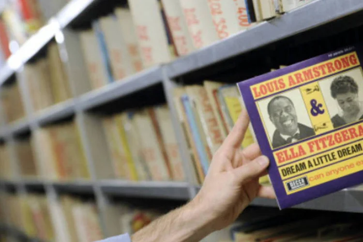 Em uma biblioteca de Paris, homem segura vinil de Louis Armstrong e Ella Fitzgerald (MIGUEL MEDINA/AFP/Getty Images)