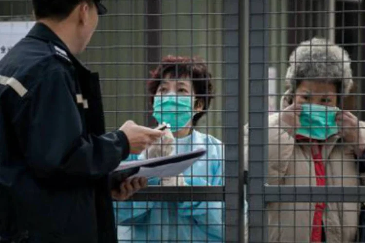 Policial conversa com mulheres infectadas com o vírus H7N9: anúncio ocorre um dia depois do sacrifício de 22 mil aves em consequência da doença (Philippe Lopez/AFP)