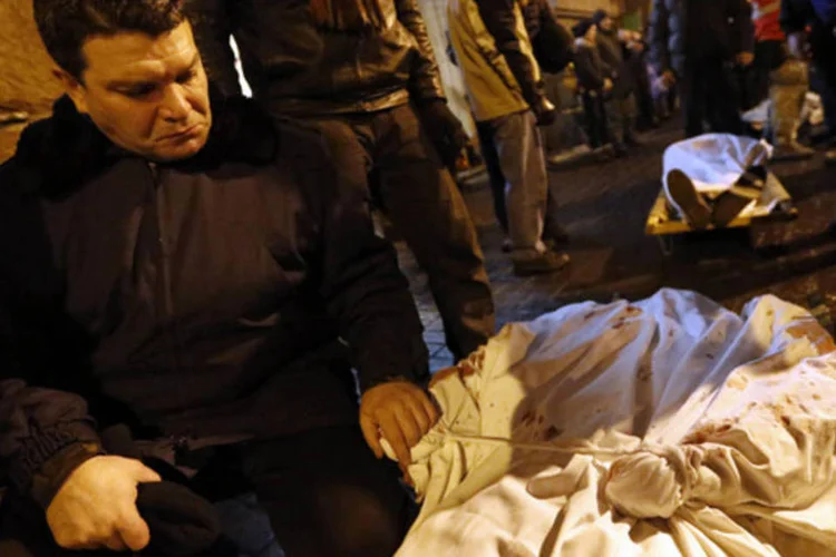 Homem segura a mão de seu filho, que morreu durante os protestos violentos na Praça da Independência, em Kiev, na Ucrânia (Yannis Behrakis/Reuters)