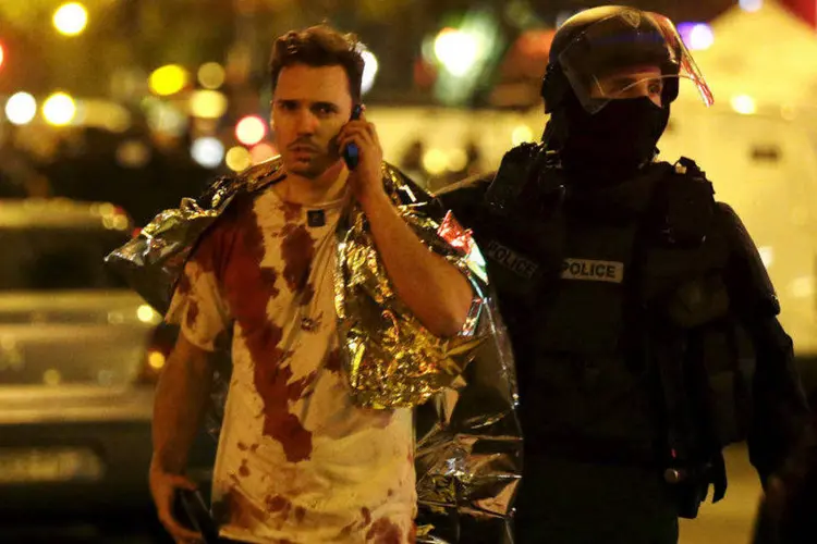 
	Homem ferido &eacute; acompanhado por policial ap&oacute;s ataques em Paris
 (Philippe Wojazer/Reuters)