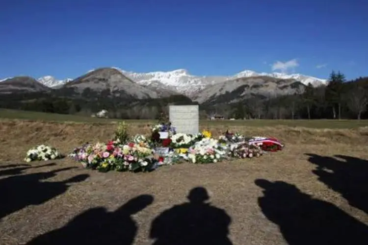 Pessoas observam memorial às vítimas pelo acidente com o Airbus A320, da Germanwings, tendo os Alpes franceses ao fundo, local do acidente (Jean Christophe Magnenet/AFP)