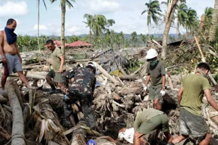 Pessoas procuram corpos nos locais destruídos pelo tufão Bopha, nas Filipinas (Erik De Castro/Reuters)