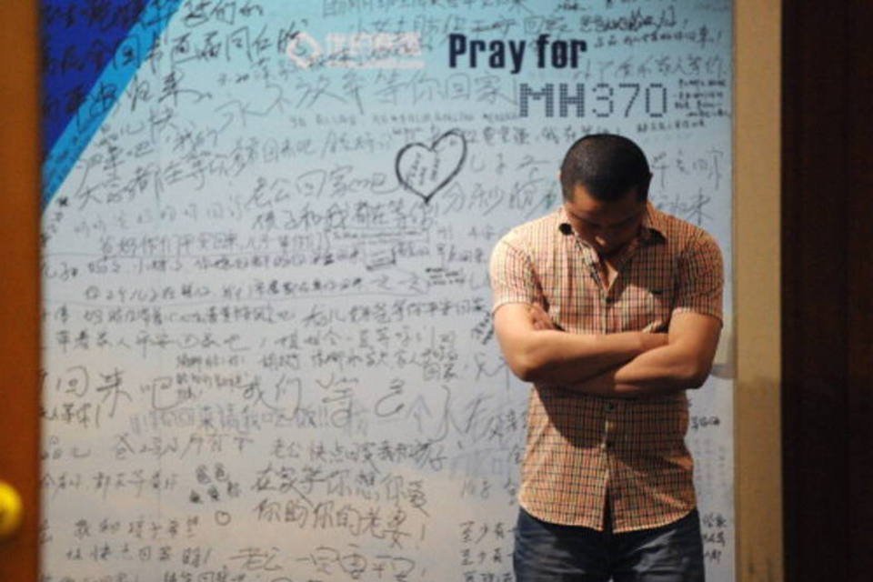 Homem em frente a painel com mensagens de apoio às vítimas do voo MH370 (AFP/Getty Images)